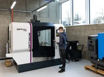 Studentas apžiūri CNC frezavimo stakles "Optimill" mechanikos dirbtuvių erdvėje